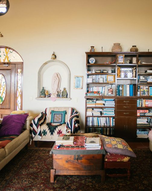 The shelving wall before: crowded shelves and mismatched furniture