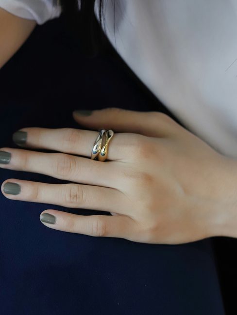 A hand resting on a navy cushion, wearing a slim gold ring