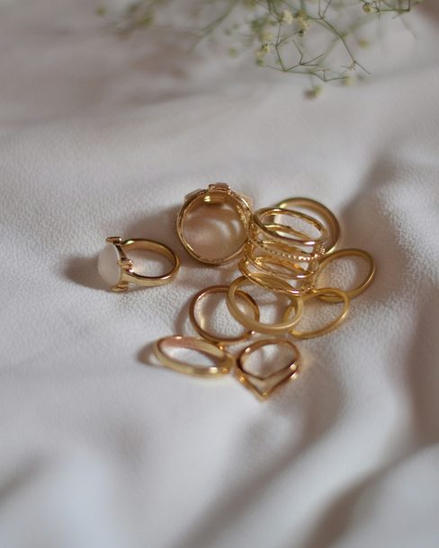 A set of thin gold stacking rings on a white linen sheet