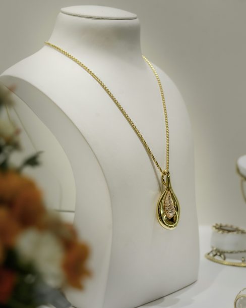 A teardrop pendant on a fine gold chain, shown on a white bust