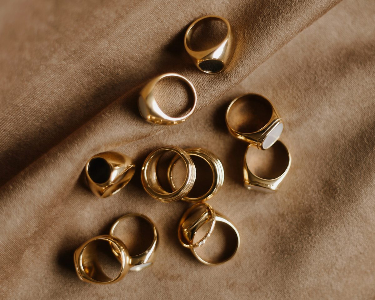 A scatter of gold rings on a soft tan cloth