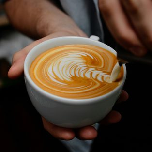 A barista pouring a tulip into a white cup