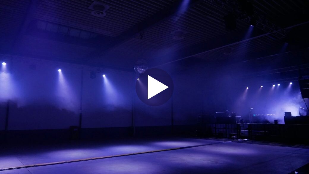 An empty stage washed in violet light, keynote video thumbnail