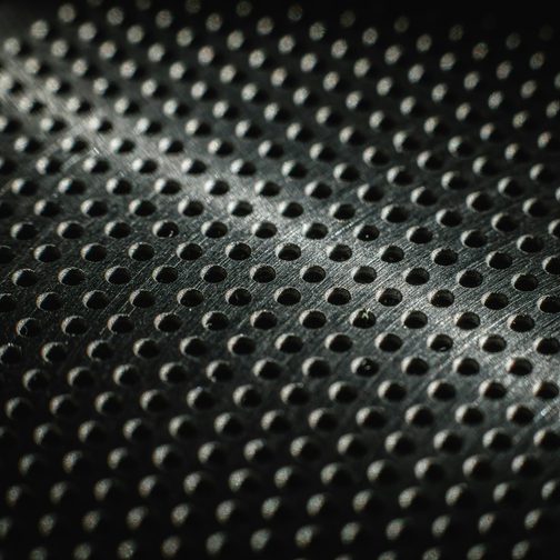 Close-up of a perforated matte black metal surface