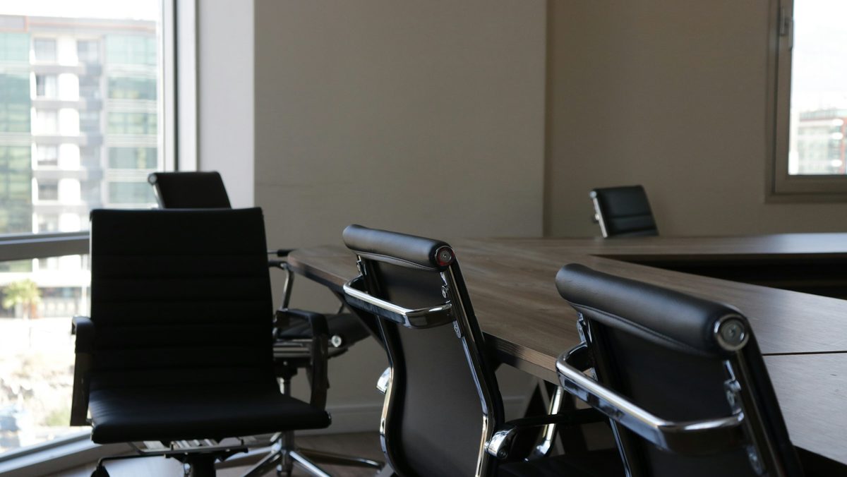 An empty meeting room with a long table and leather chairs by a window