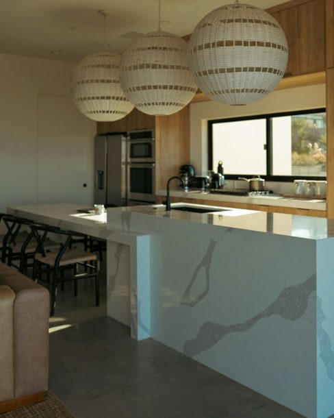 The renovated kitchen with pendant lights and a marble island