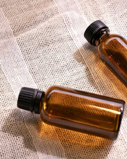 Two amber glass serum bottles on linen
