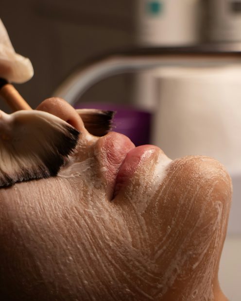 A soft brush applying a cream mask during a facial