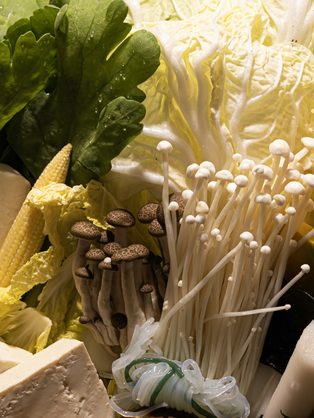 Fresh greens, mushrooms and tofu laid out for a shared hot pot