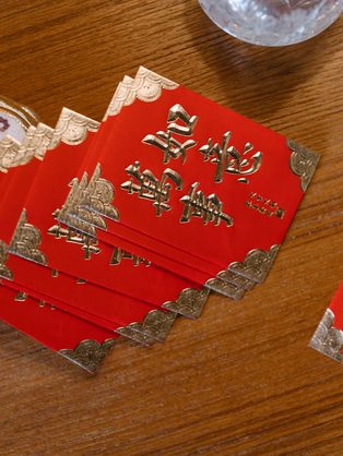 Red envelopes with gold lettering fanned on a wooden table