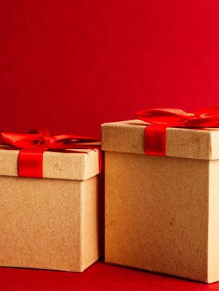 Two kraft gift boxes tied with red ribbon on red