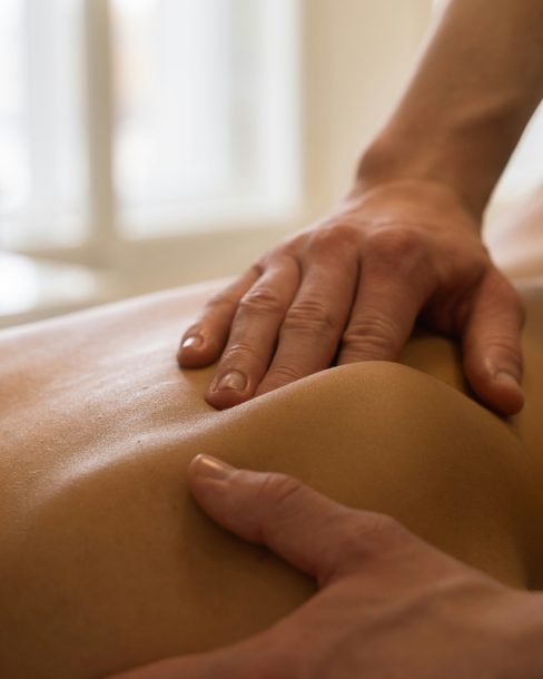 A therapist's hands working on a client's shoulder