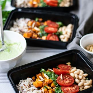 Three trays of roasted vegetables, beans and rice