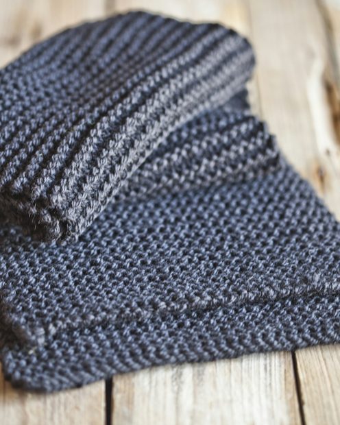 A folded charcoal wool scarf on weathered boards