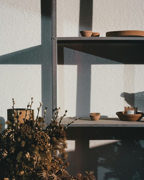 Handmade bowls and cups on open shelves in warm afternoon light