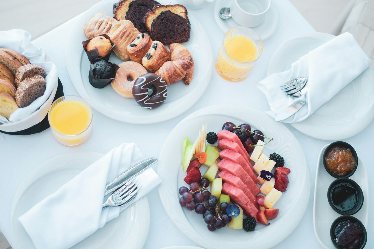 A sunlit brunch table with pastries, fruit and orange juice
