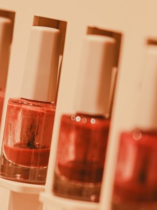 A row of coral and red polishes in a white display