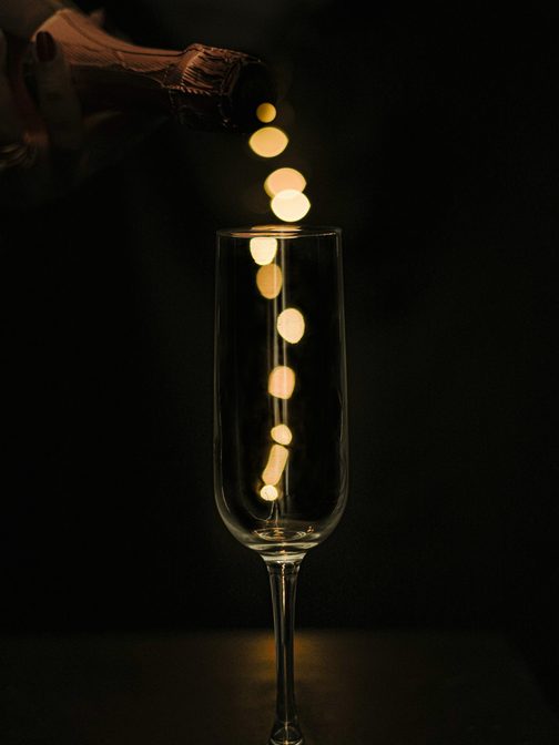 Champagne poured into a tall flute against a dark background