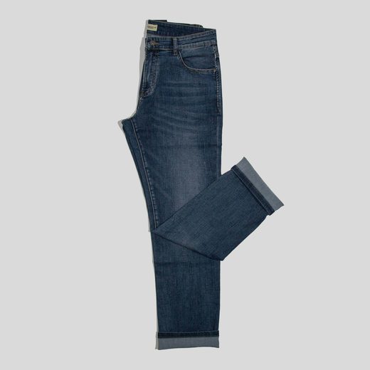 A pair of dark blue jeans laid flat on a gray ground