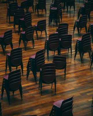 Rows of stacked chairs set out in a hall