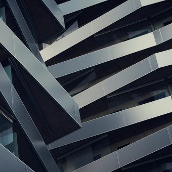 A modern building's angled balconies shot from below in hard light
