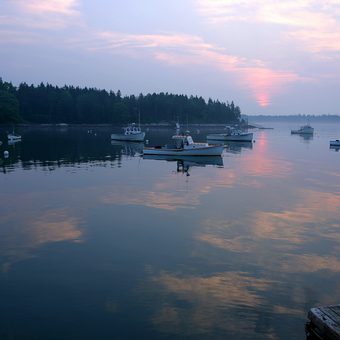 Fishing boats anchored in a calm harbor at sunrise