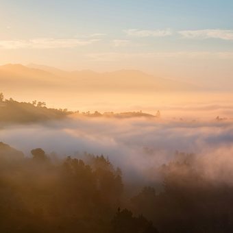 A mountain ridge at sunrise with fog in the valleys