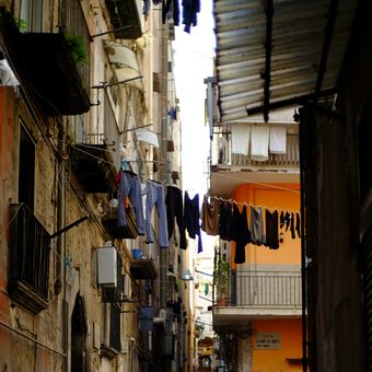 A narrow alley with laundry lines between weathered buildings