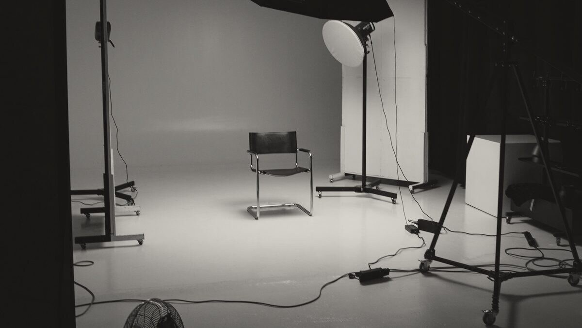 An empty photography studio with a backdrop, a chair and a single light