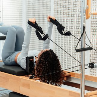 A client on her back, legs in the reformer straps