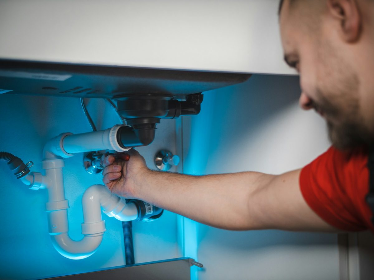 A plumber fixing the pipes under a bathroom sink