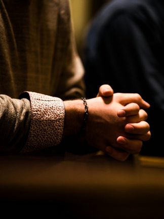 Clasped hands resting on a table in warm light