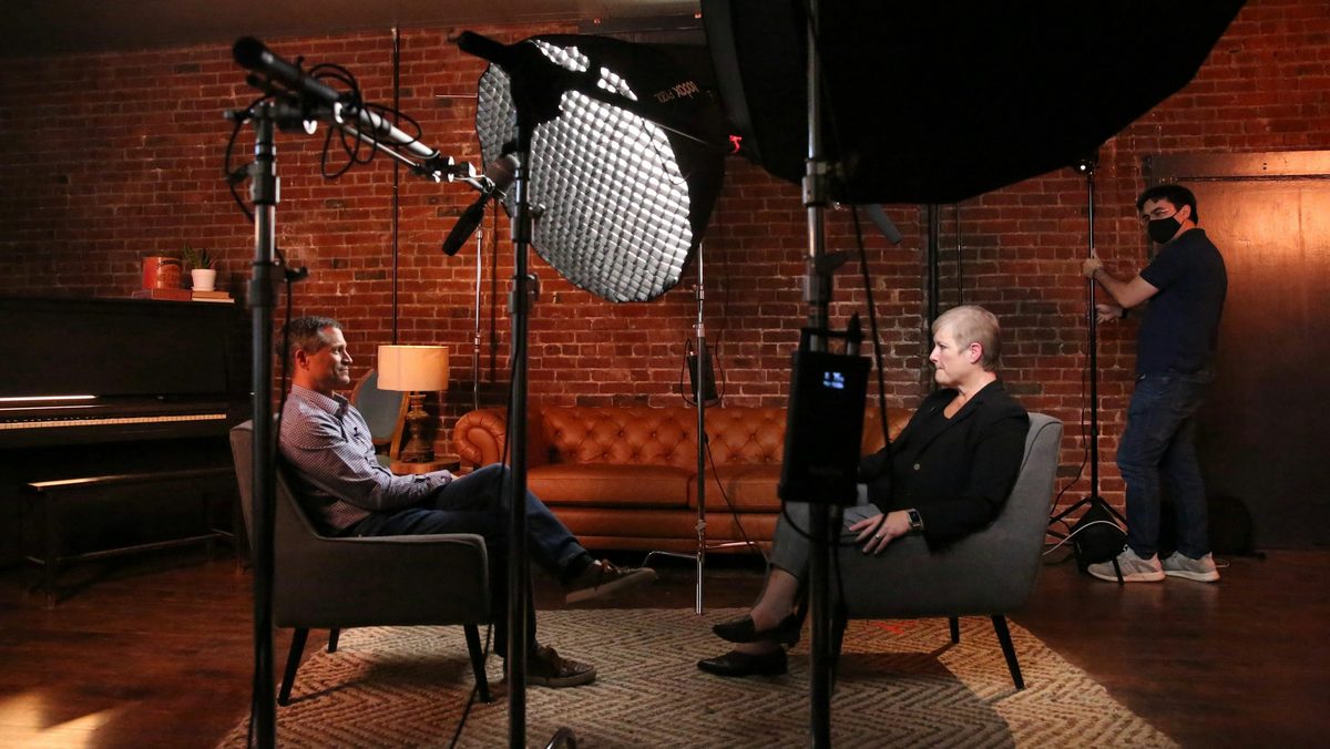 Two people talking in armchairs in a warmly lit recording studio