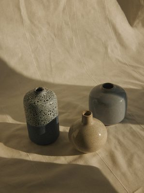 Three speckled stoneware bud vases on linen