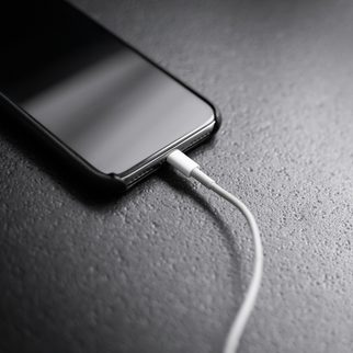 A phone on a charging cable on a gray desk