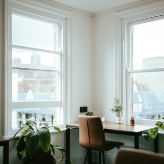 A calm, empty room with a desk by a tall window