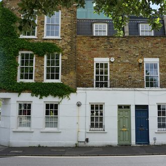 A row of well-kept brick buildings with ivy and painted front doors