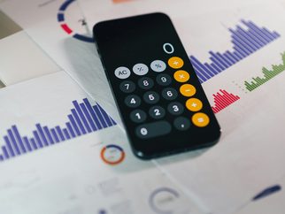 A calculator resting on printed financial charts
