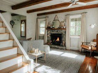 A bright living room with a fireplace beside the stairs