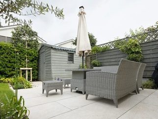 A paved patio with garden chairs and a lawn