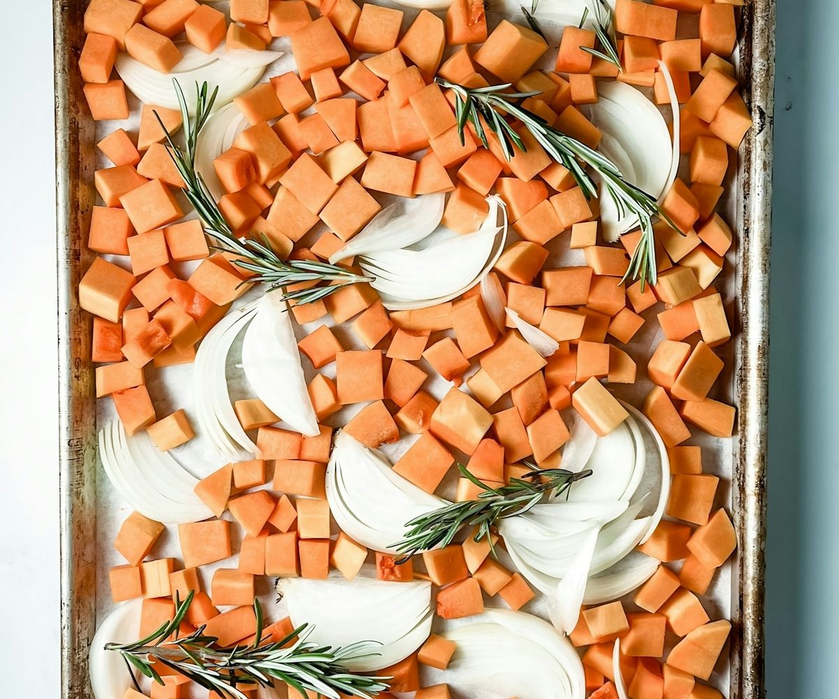 Diced sweet potato and onion with rosemary on a sheet pan