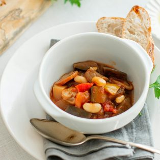 A bowl of bean stew with crusty bread on the side