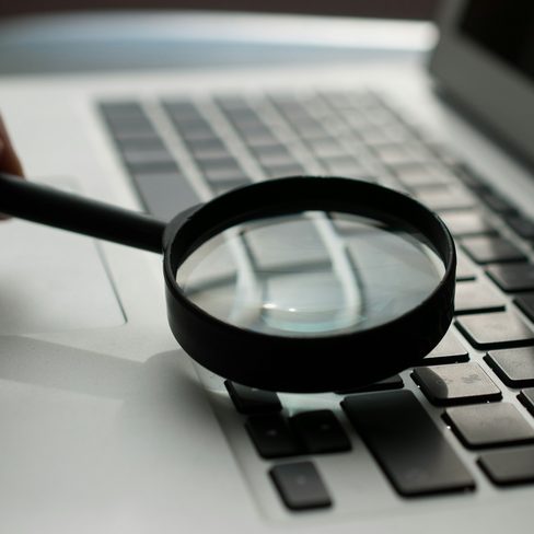 A magnifying glass held over a laptop keyboard