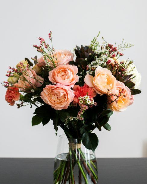 A loose bouquet of peach roses in a clear glass vase