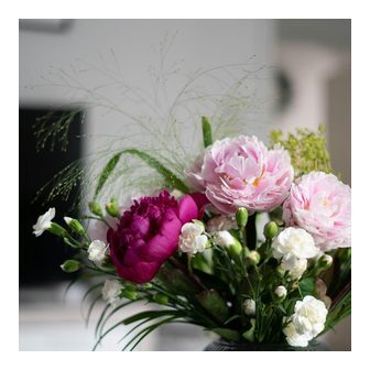 Peonies in a ribbed glass vase on a green side table