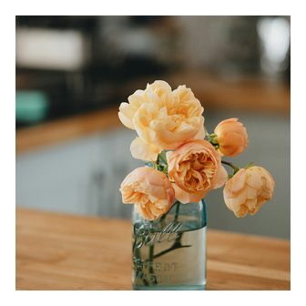 Pale roses in a glass bottle on a wooden table
