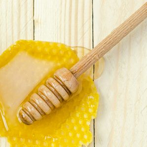 A honey dipper resting on a piece of honeycomb