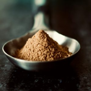 A spoonful of cocoa powder on a dark counter