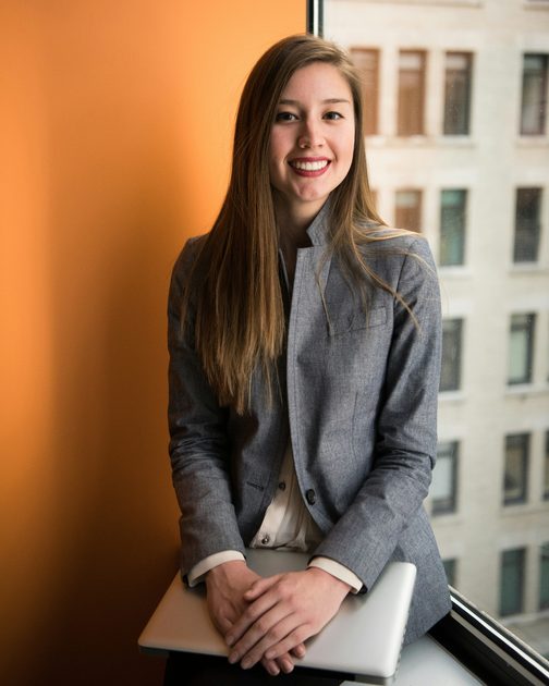 Hannah Voss sitting by an office window with her laptop