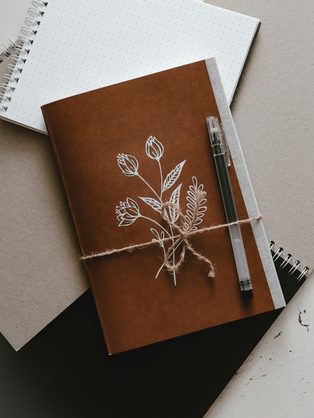 A kraft notebook tied with string, with a pen and a sketchbook